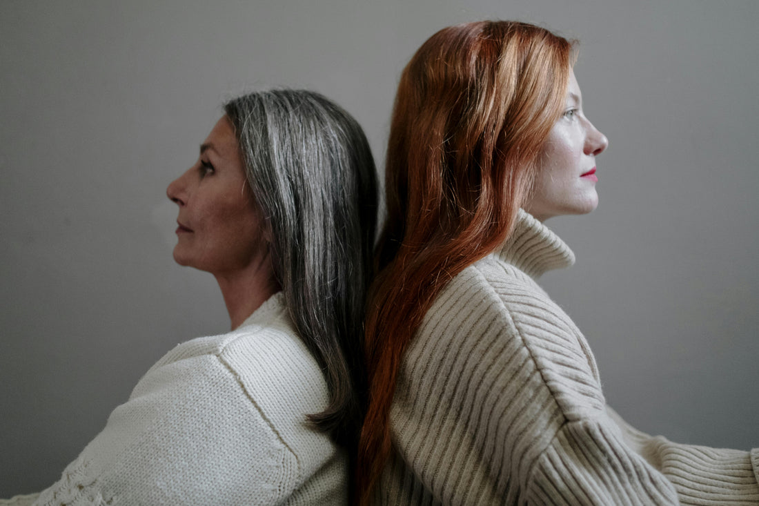 Two women standing back to back, calm and reflective, representing resilience and the impact of chronic stress on women's health