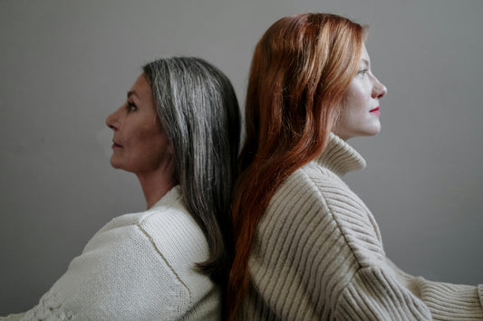 Two women standing back to back, calm and reflective, representing resilience and the impact of chronic stress on women's health